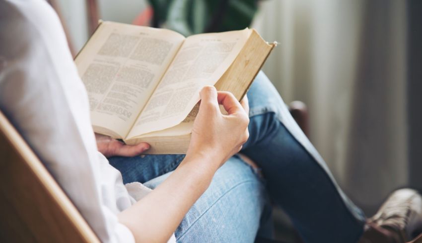 A woman is sitting in a chair reading a book.