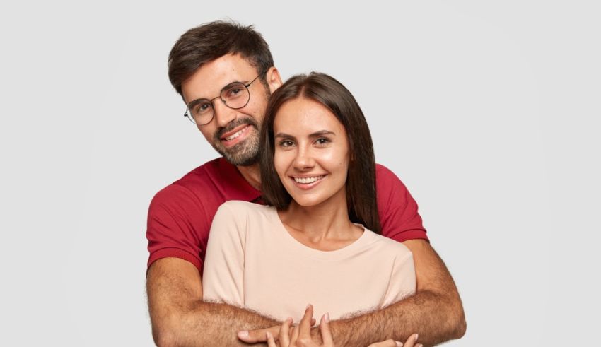 A man and woman hugging each other on a gray background.