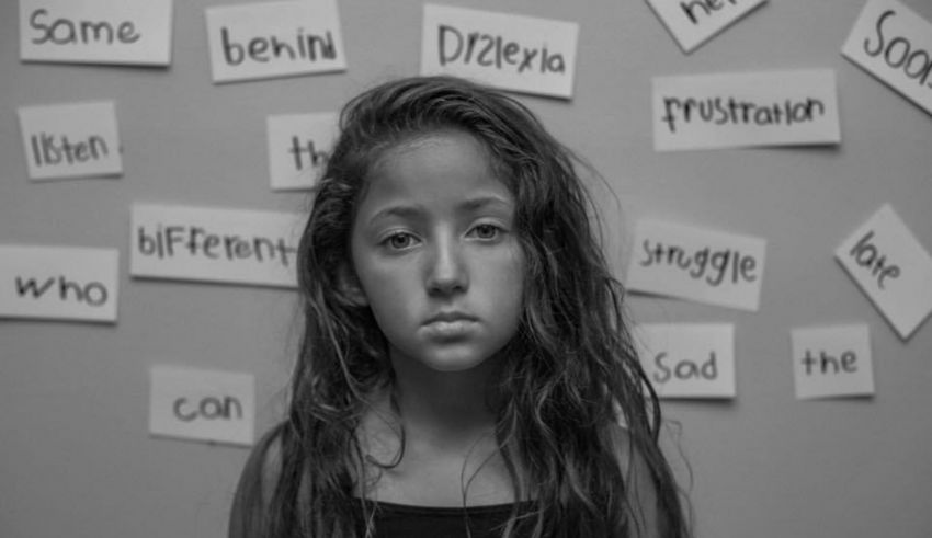A girl with long hair standing in front of a wall with words.