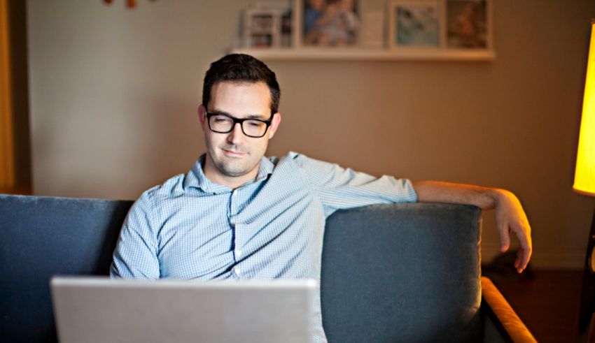 A man sitting on a couch using a laptop.