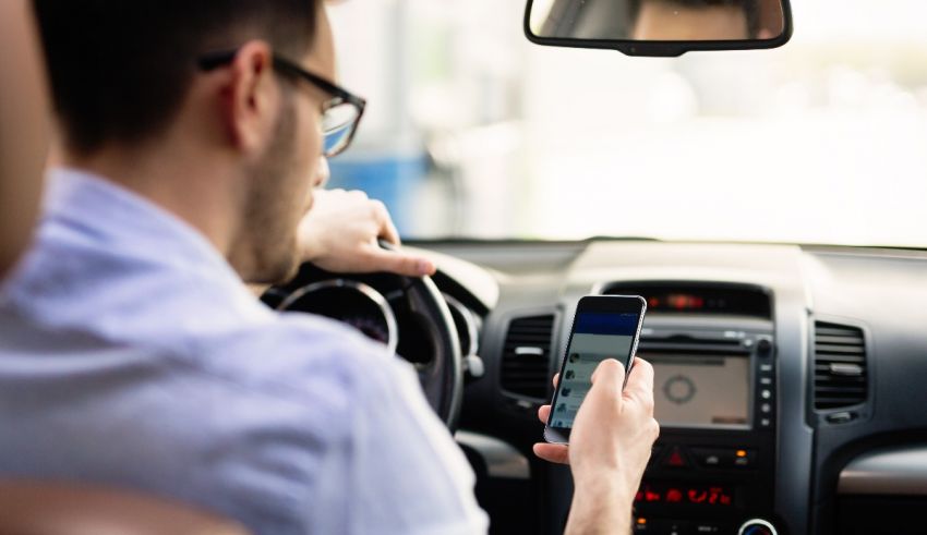 A man is using his cell phone while driving a car.