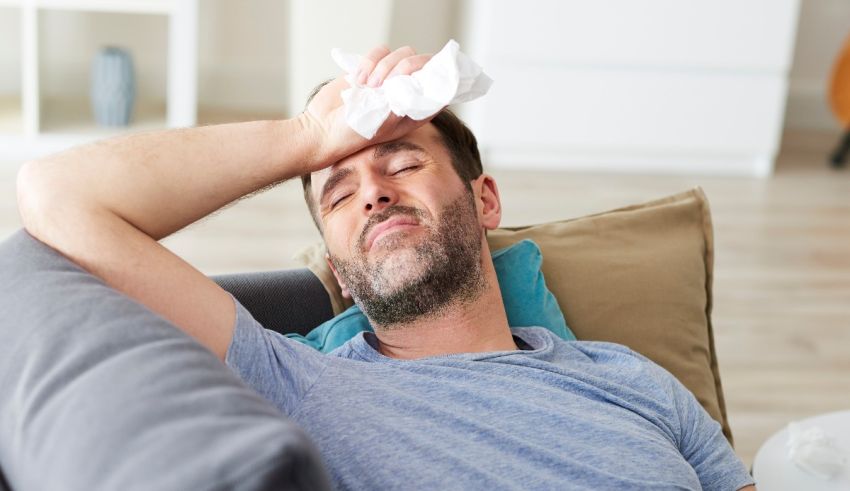 A man laying on a couch with a tissue in his hand.