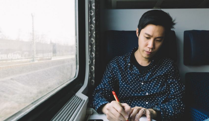 A man sitting in a chair writing on a paper.