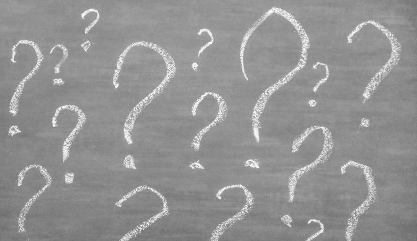 Question marks drawn on a blackboard.