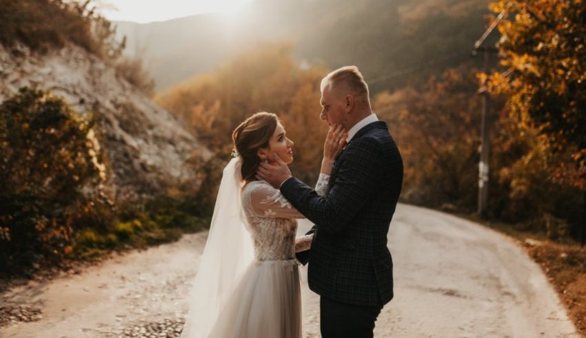 A bride and groom embrace on a dirt road in autumn.