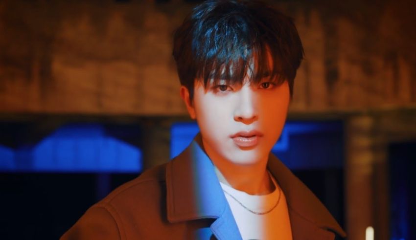 A man in a jacket is standing in front of a blue light.