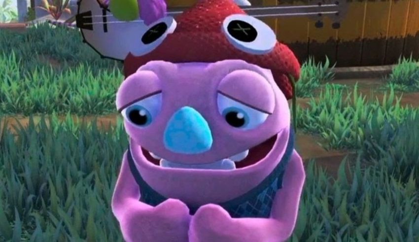 A purple stuffed animal is standing next to a grassy field.