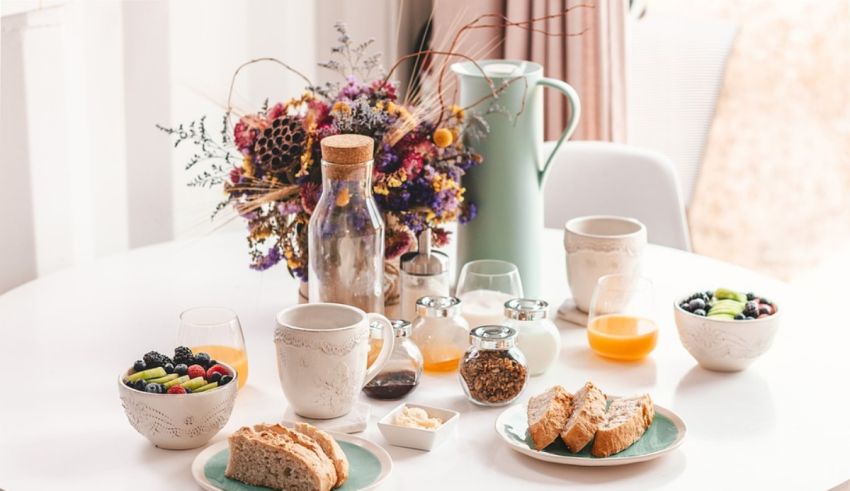 Breakfast on a white table with fruit, bread and juice.