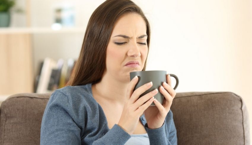 A woman sitting on a couch with a cup of coffee.