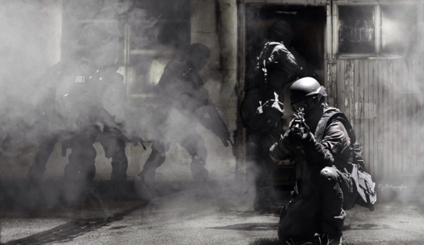 A soldier is kneeling down in front of smoke.