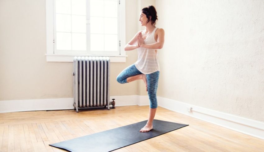 A woman doing a yoga pose in an empty room.