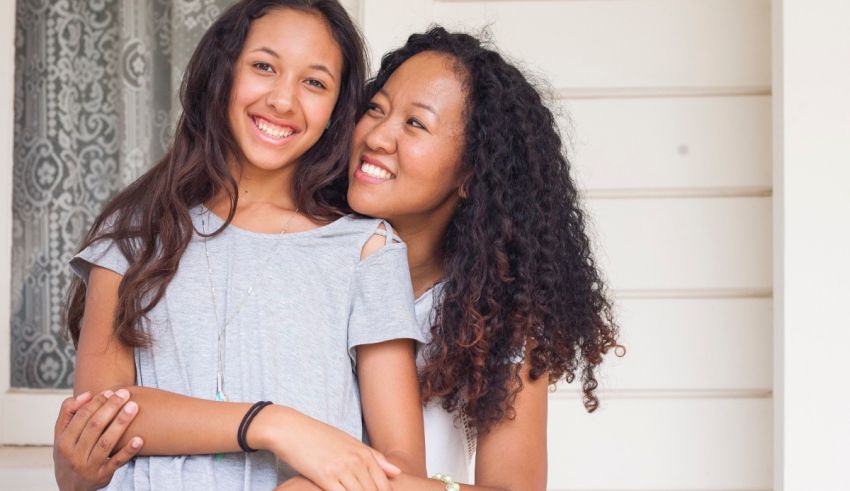 Two young women hugging each other in front of a house.
