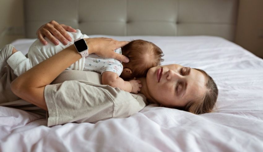 A woman laying on a bed with a baby in her arms.