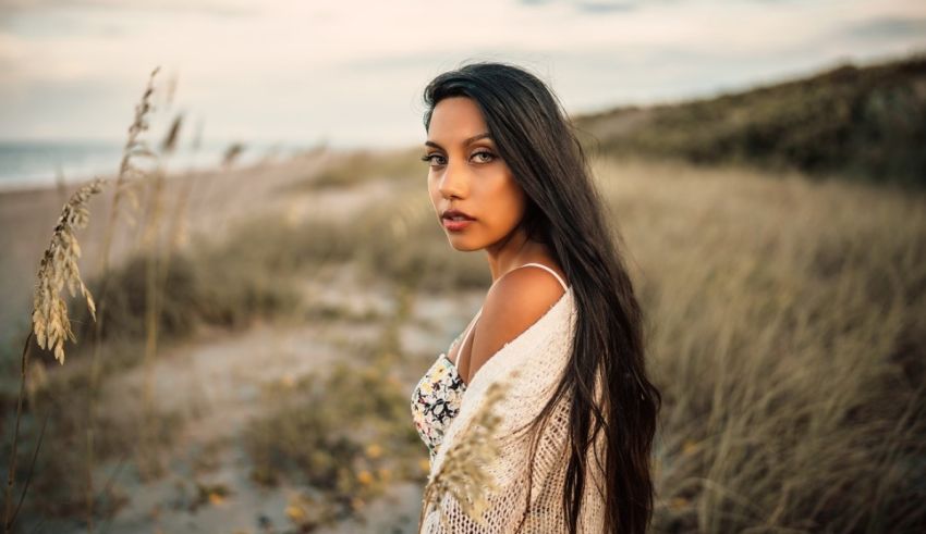 A young woman standing in the sand on the beach.