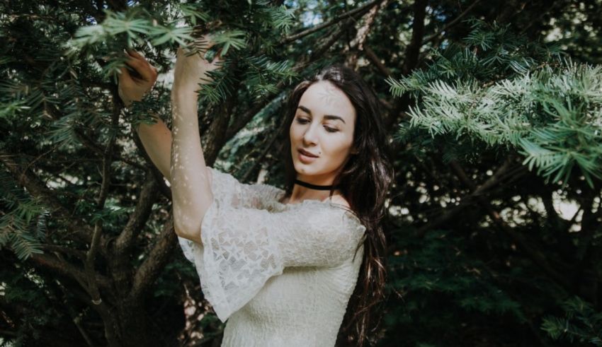 A woman in a white dress is holding a tree.