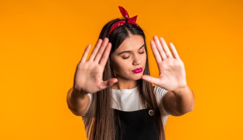 A woman with a stop sign on her hands on an orange background.