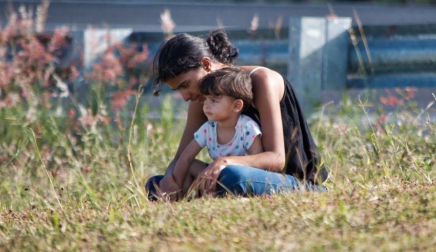 A woman and a child sitting in the grass.