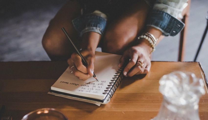 A woman writing in a notebook with a pen.
