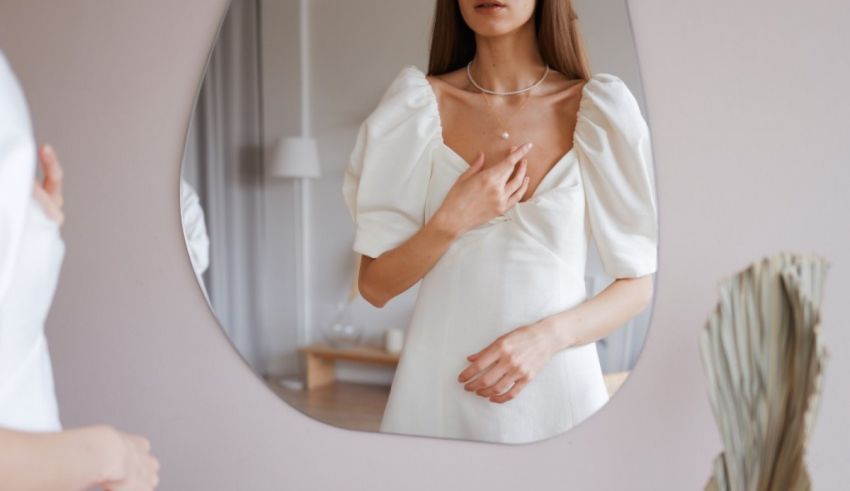 A woman in a white dress is looking at herself in the mirror.