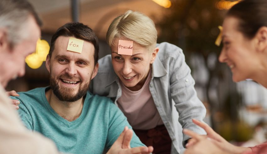 A group of people sitting around a table with sticky notes on their heads.
