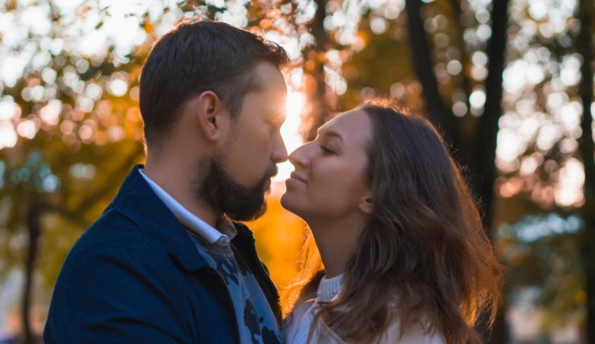 A couple is kissing in the park at sunset.