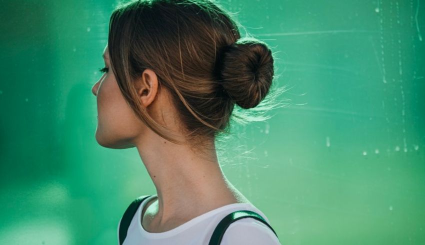 A woman with a bun in her hair looking at a green wall.