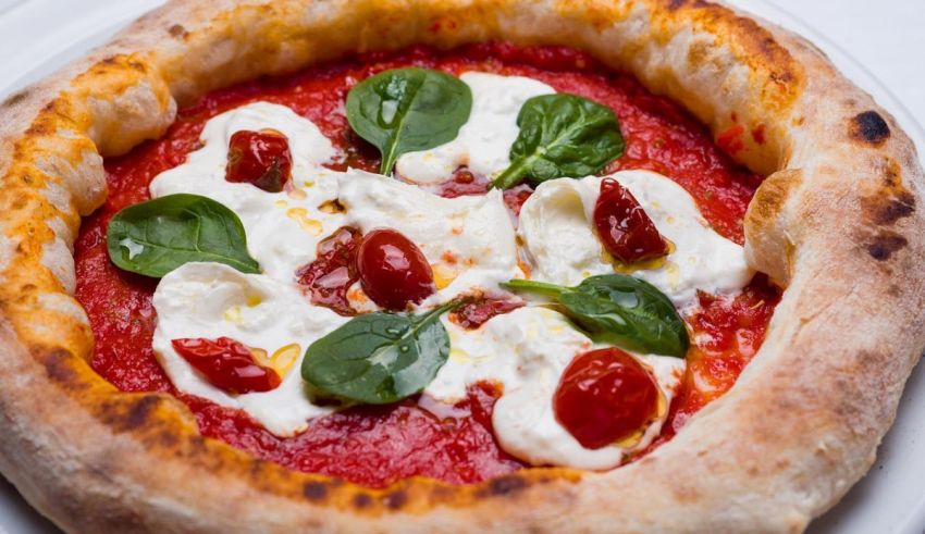 A pizza with tomatoes, mozzarella and basil on a white plate.