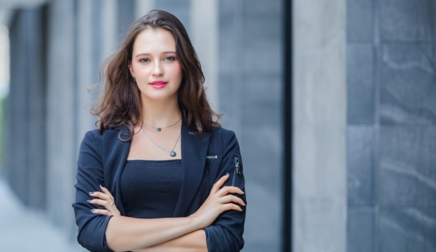 A young business woman with her arms crossed in front of a building.