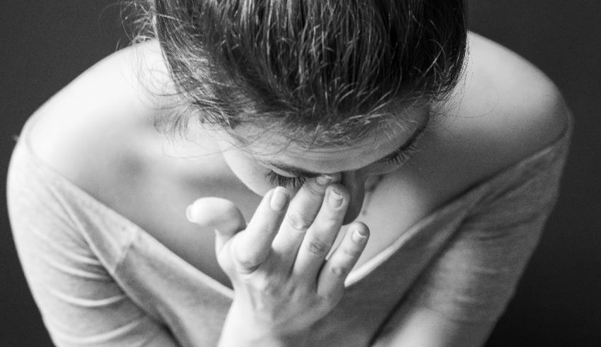 A black and white photo of a woman covering her face.