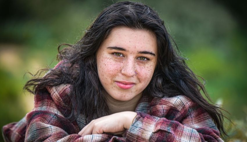 A girl in a plaid shirt laying on the grass.