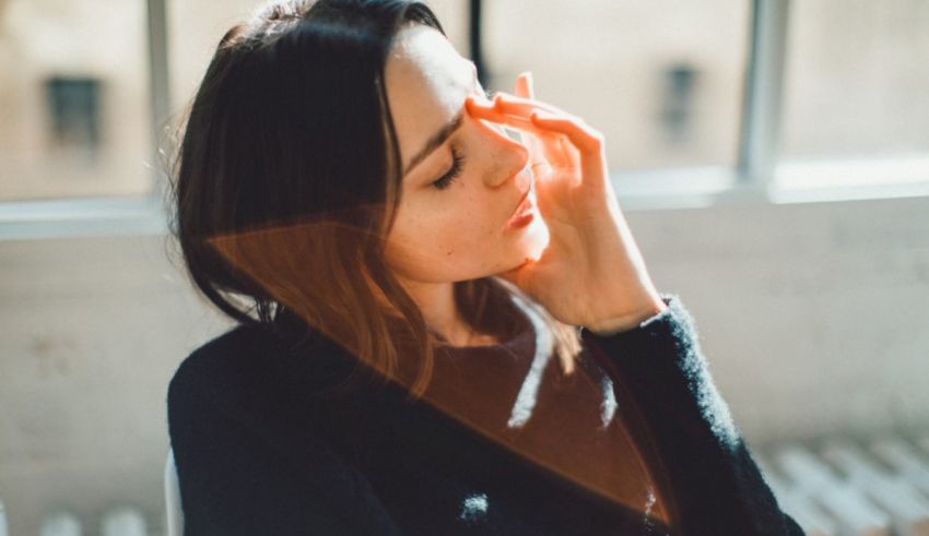 A woman holding her hand in front of a window.