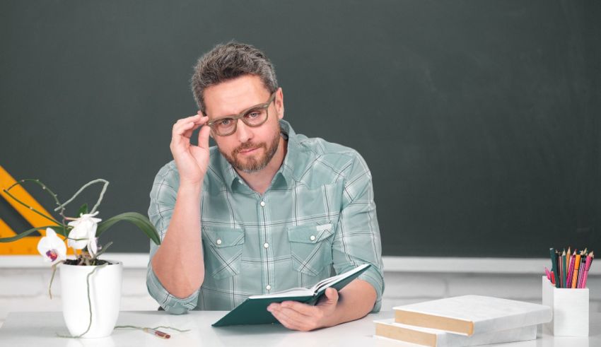 A man sitting at a desk reading a book.