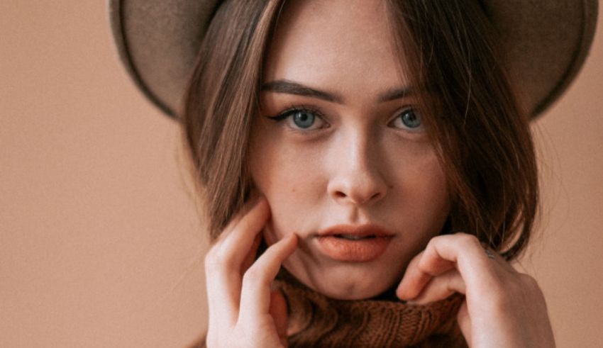 A woman in a hat posing with her hand on her face.