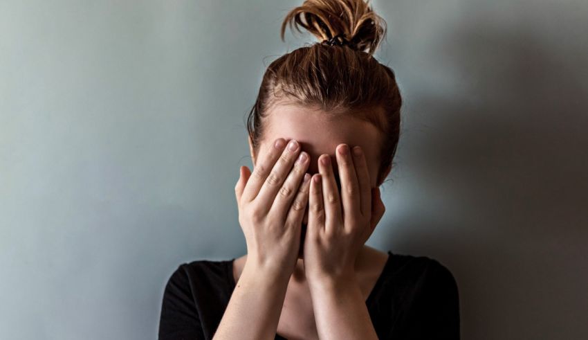 A woman covering her face with her hands.