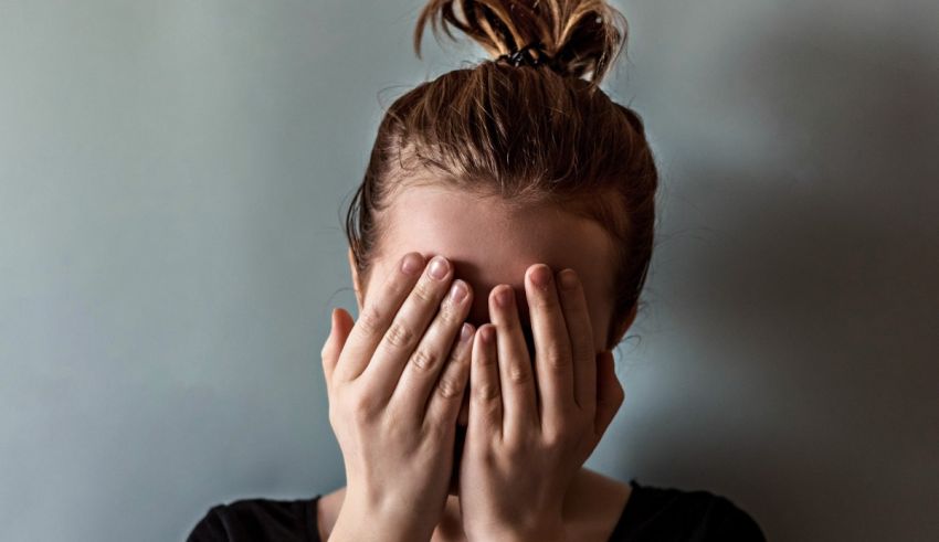 A woman covering her face with her hands.
