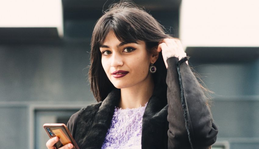 A woman holding a cell phone while walking down the street.