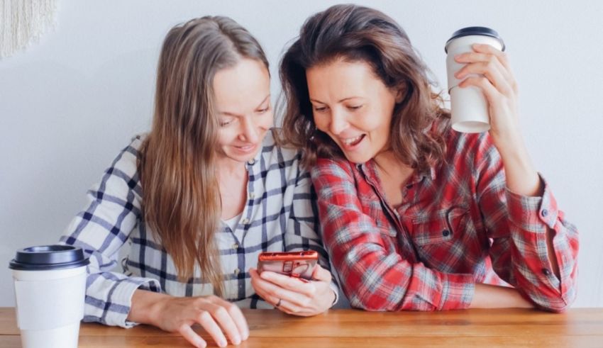 Two women sitting at a table looking at their phones.