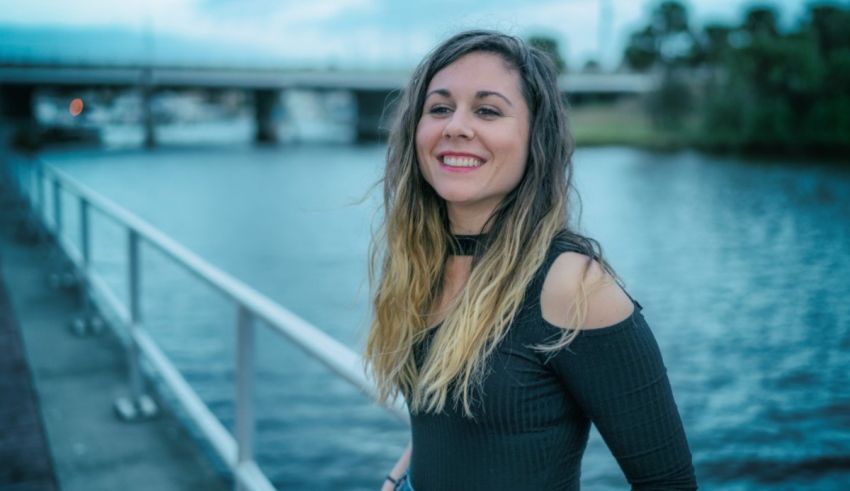 A woman standing on a railing near a body of water.