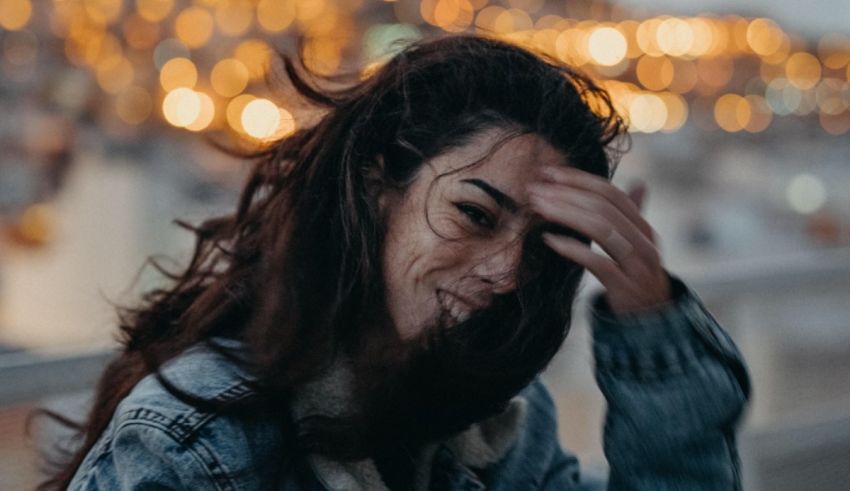 A woman is holding her head up in front of a city at night.