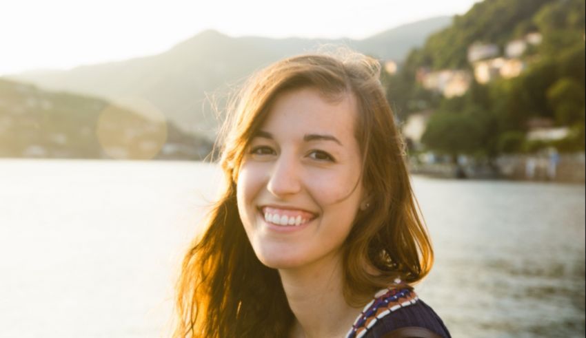 A young woman smiling in front of a lake.