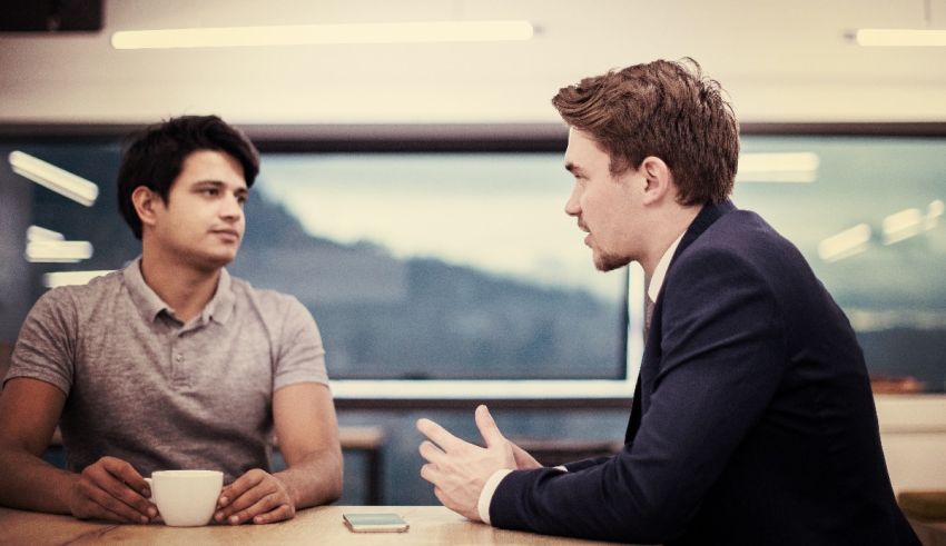 Two men talking at a table in an office.