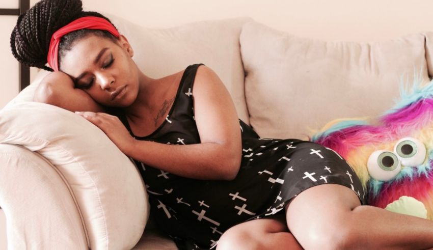 A girl sleeping on a couch with a stuffed animal.