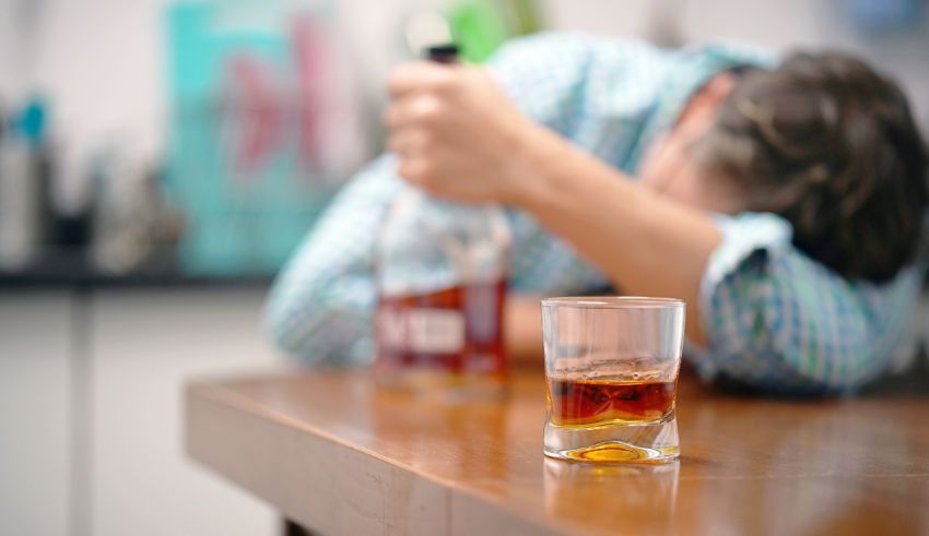 A man lying on a table with a glass of alcohol.