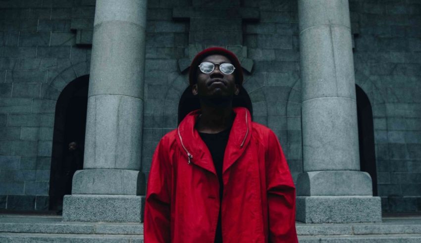A man in a red jacket standing in front of pillars.