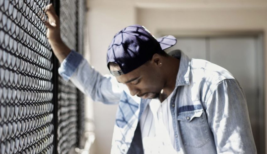 A man leaning against a metal fence.