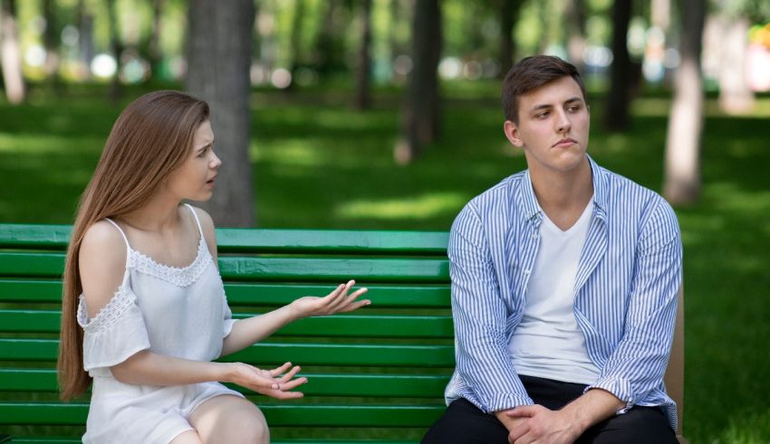 A man and woman sitting on a bench talking to each other.