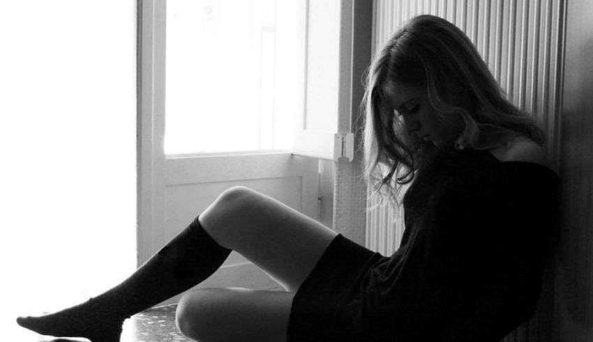 A black and white photo of a woman sitting on the floor.