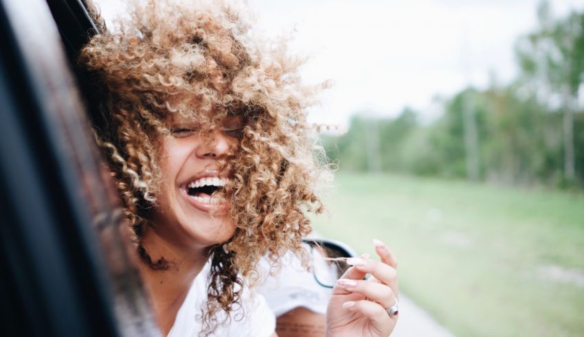 A woman laughing out of the window of a car.