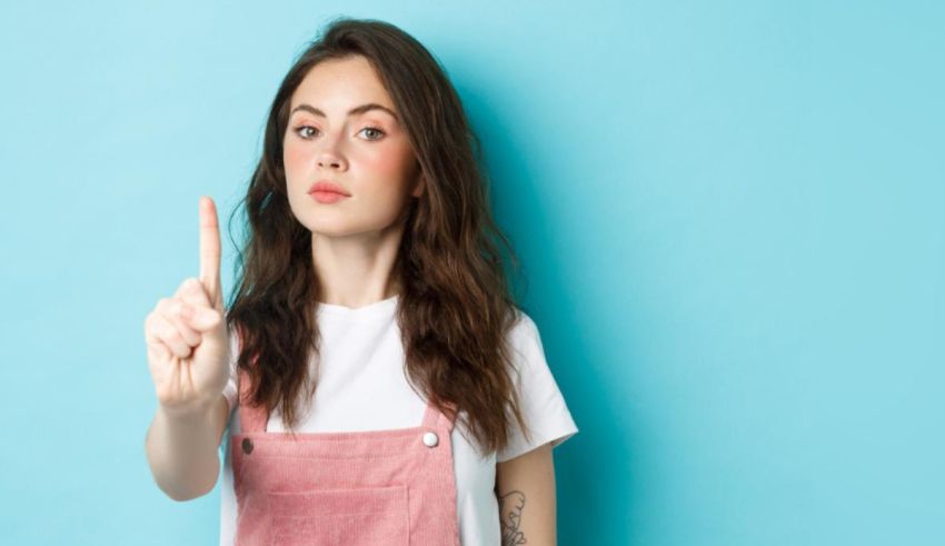 A young woman pointing at something on a blue background.