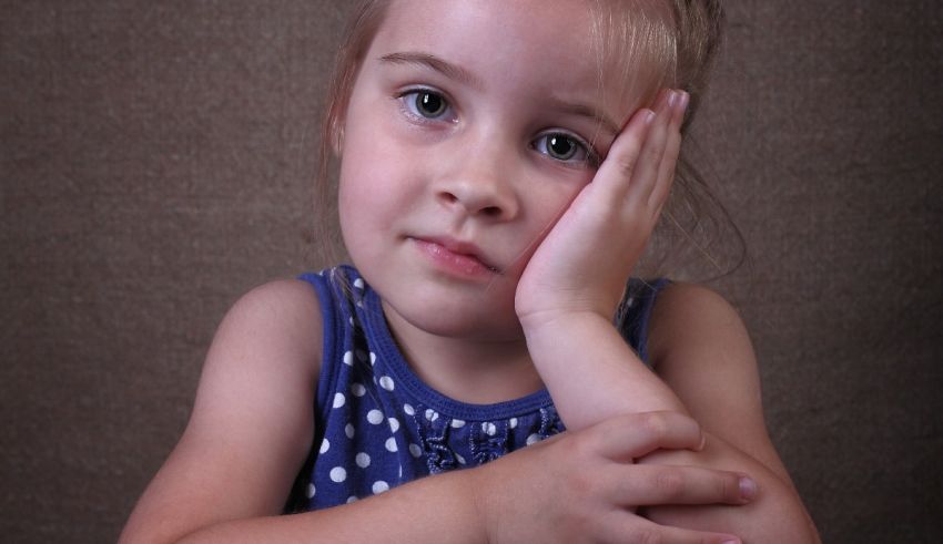 A little girl with her hand on her face.